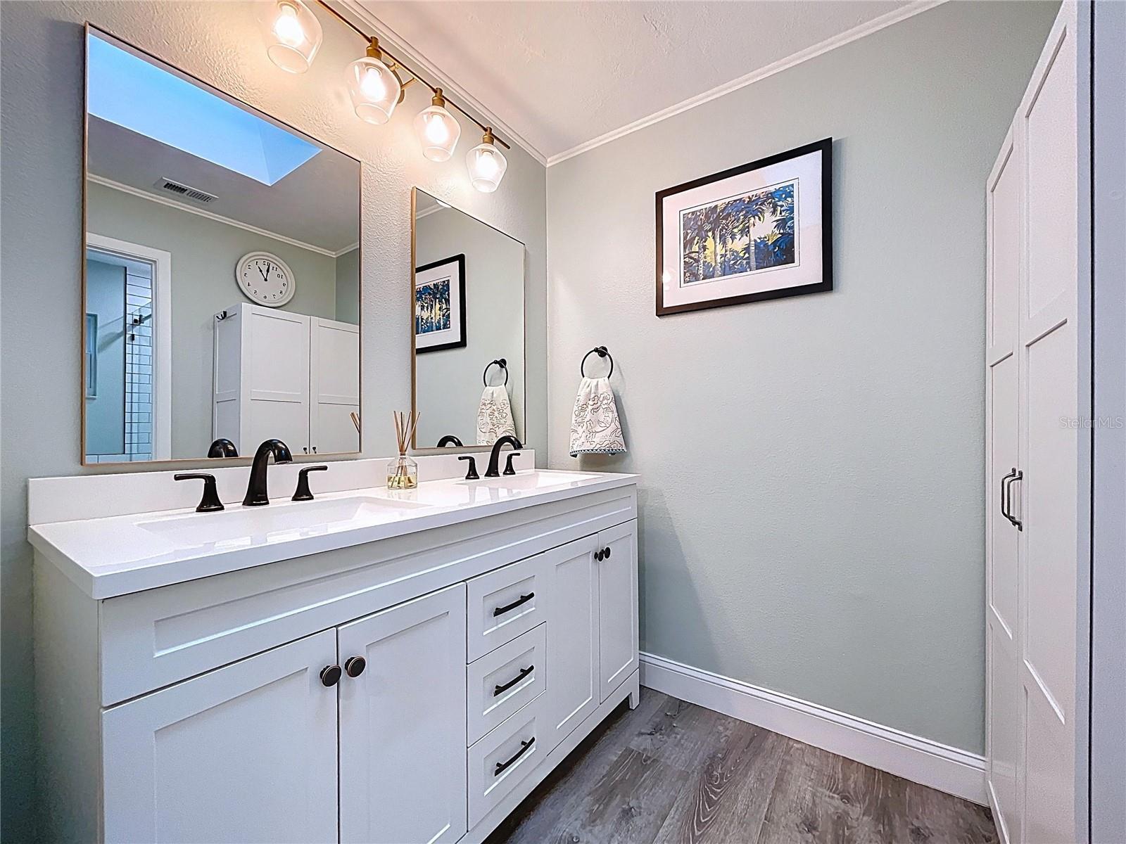 Updated en suite bath with dual vanity, stylish fixtures, and framed mirrors beneath modern lighting.