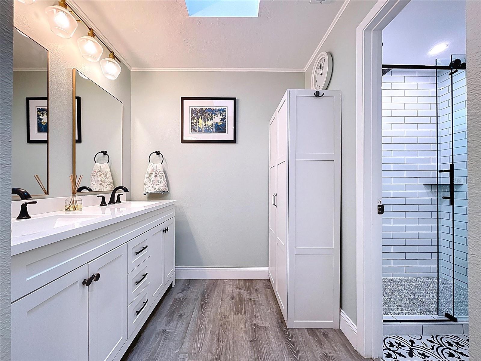 Well-appointed bathroom with shaker-style cabinetry, excellent storage, and soft overhead light from a skylight.