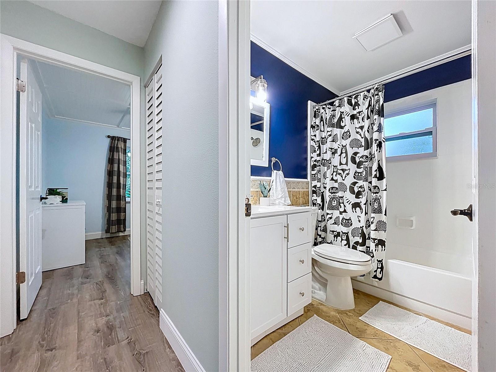 Functional layout connecting bedrooms to a full bath with deep blue accent wall and playful shower curtain for added charm.