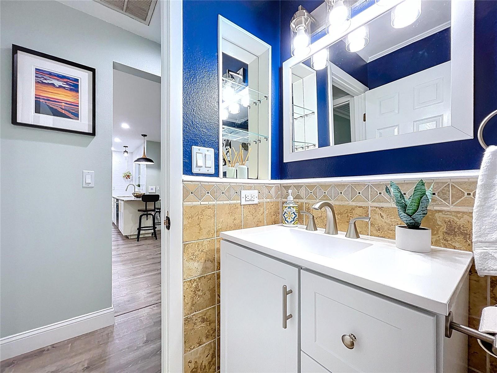 Stylish bathroom with updated vanity, brushed nickel fixtures, and tile accent wall beneath a wide framed mirror.