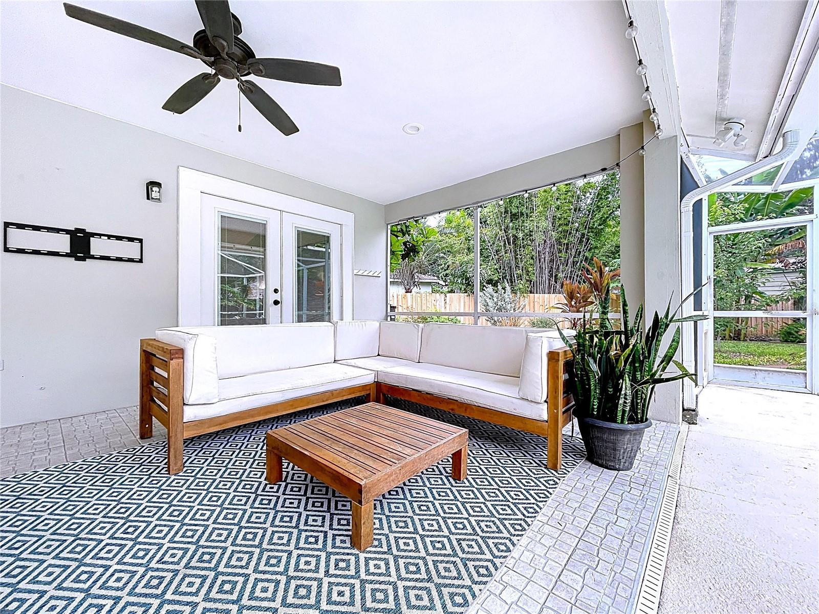 Covered outdoor lounge with ceiling fan, string lights, and tile flooring—perfect for relaxing or entertaining poolside.