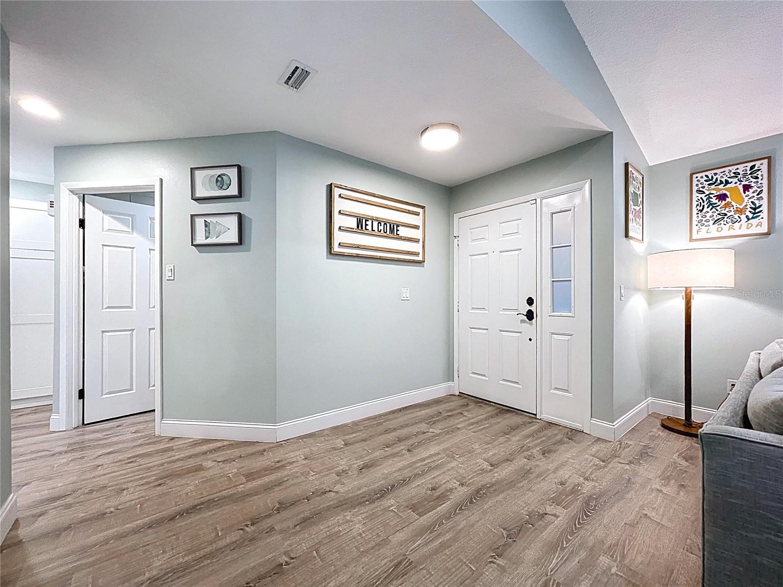 Welcoming front entry with wood-look flooring and clean lines, offering a glimpse into the home’s bright and modern interior.