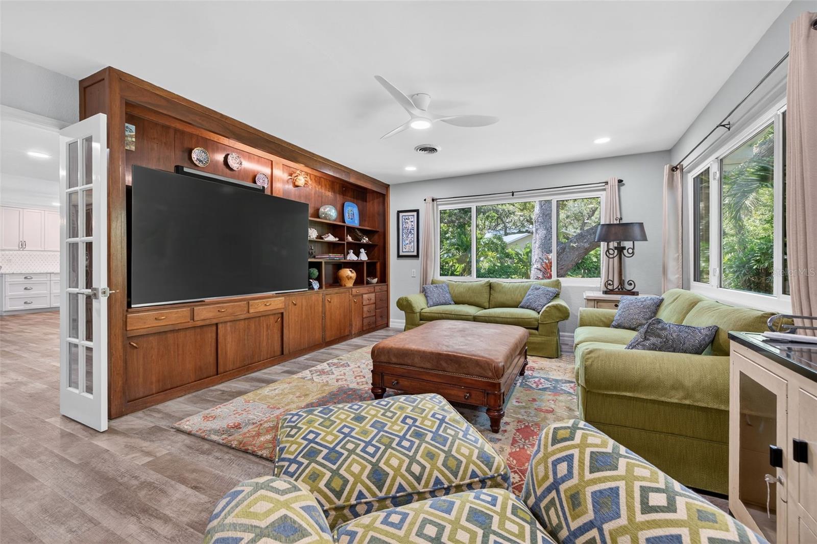 Living Room with original built in custom designed shelving and large picture windows of the Tropical Oasis in the Backyard