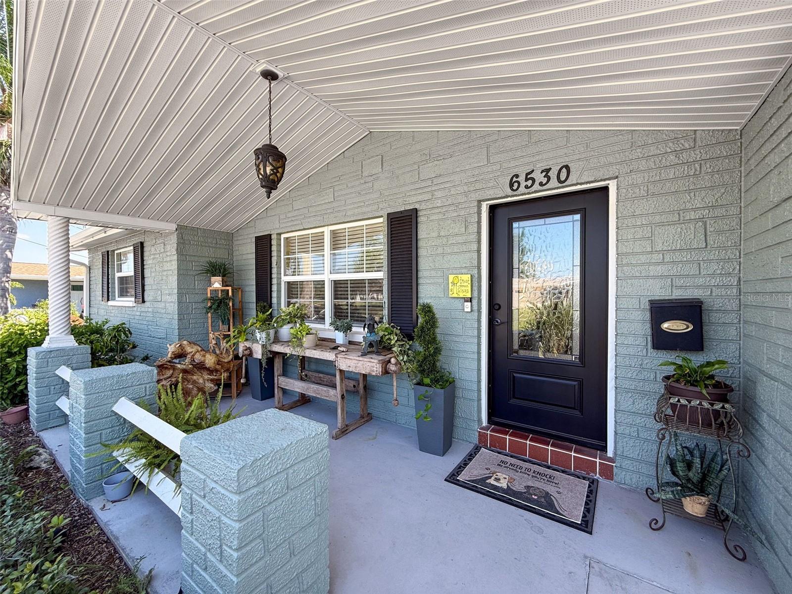 COVERED PORCH WITH A BEAUTIFUL CEILING, WITH A STUNNING FRONT DOOR.