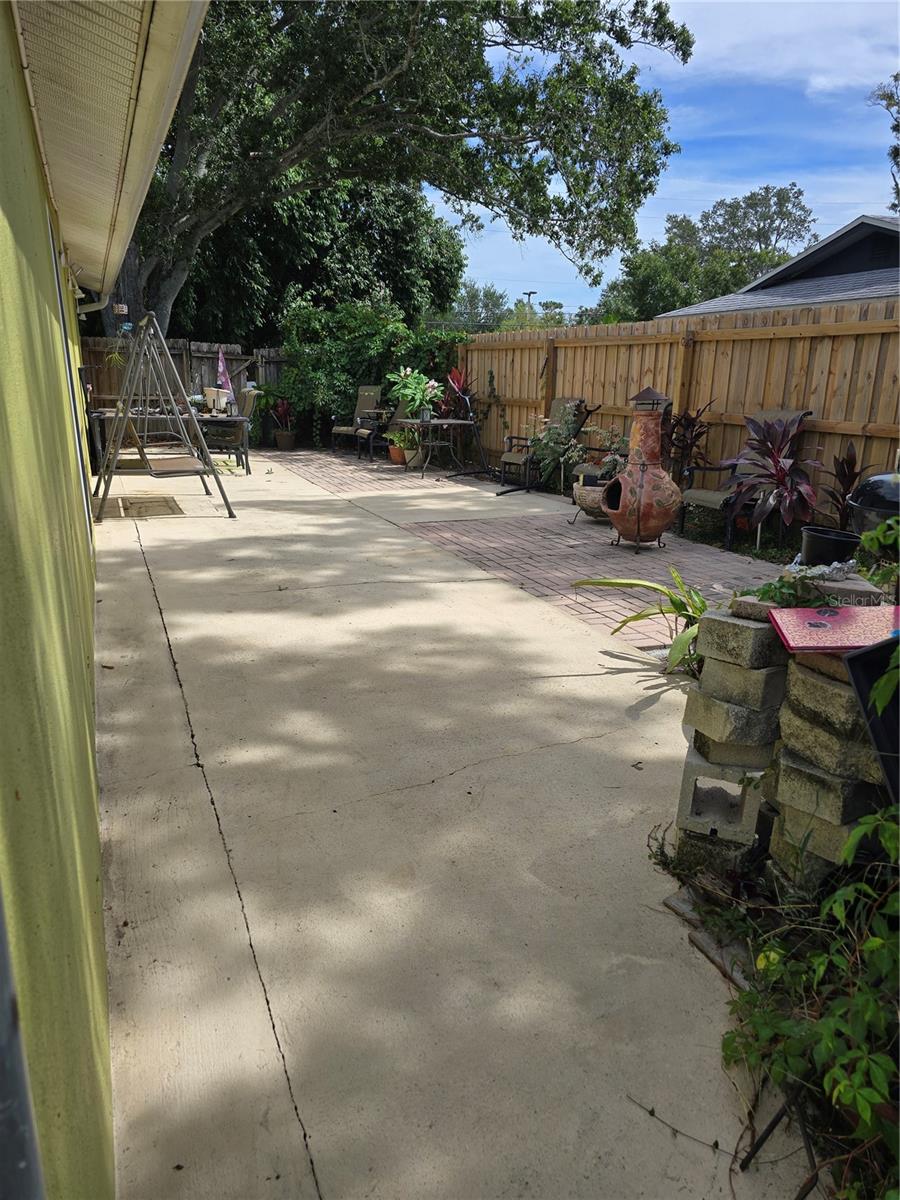 Back yard paved in center- great space for entertaining. Tall fencing so very private
