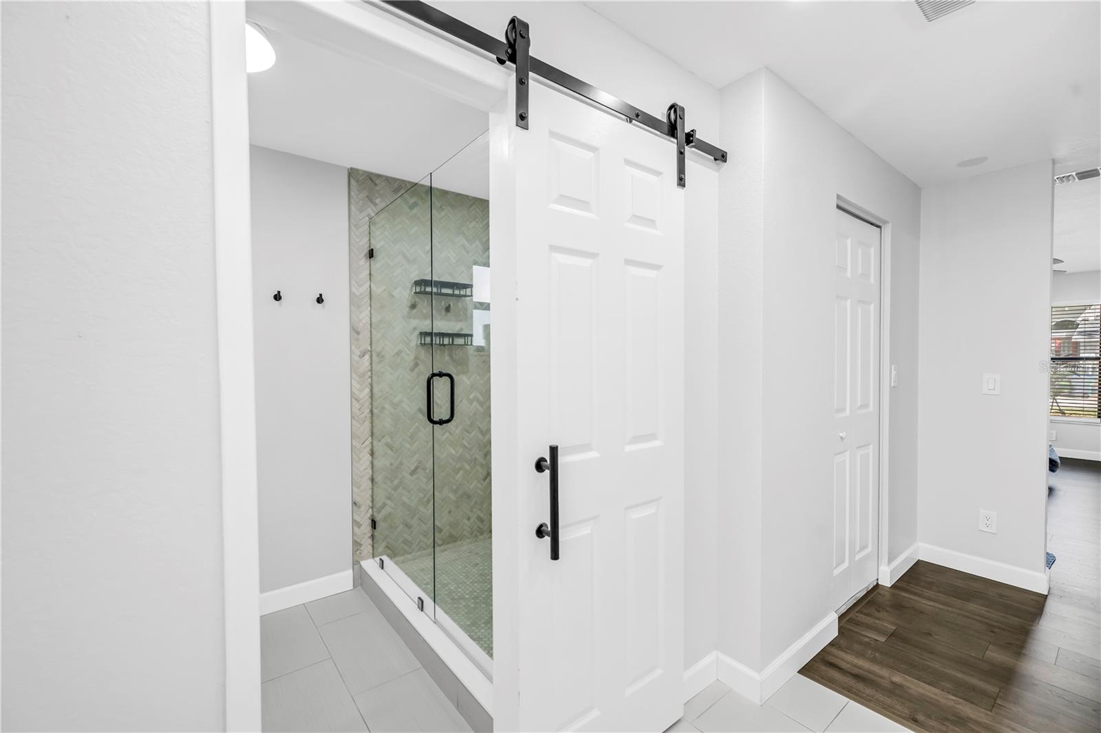 Barn door leading to primary bathroom shower & toilet