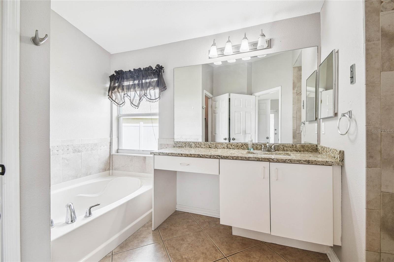 Primary bathroom has plenty of natural light with granite countertops.