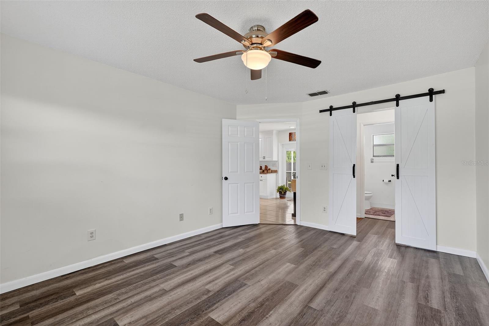 Primary Suite with barn doors leading into bath and walk in closet