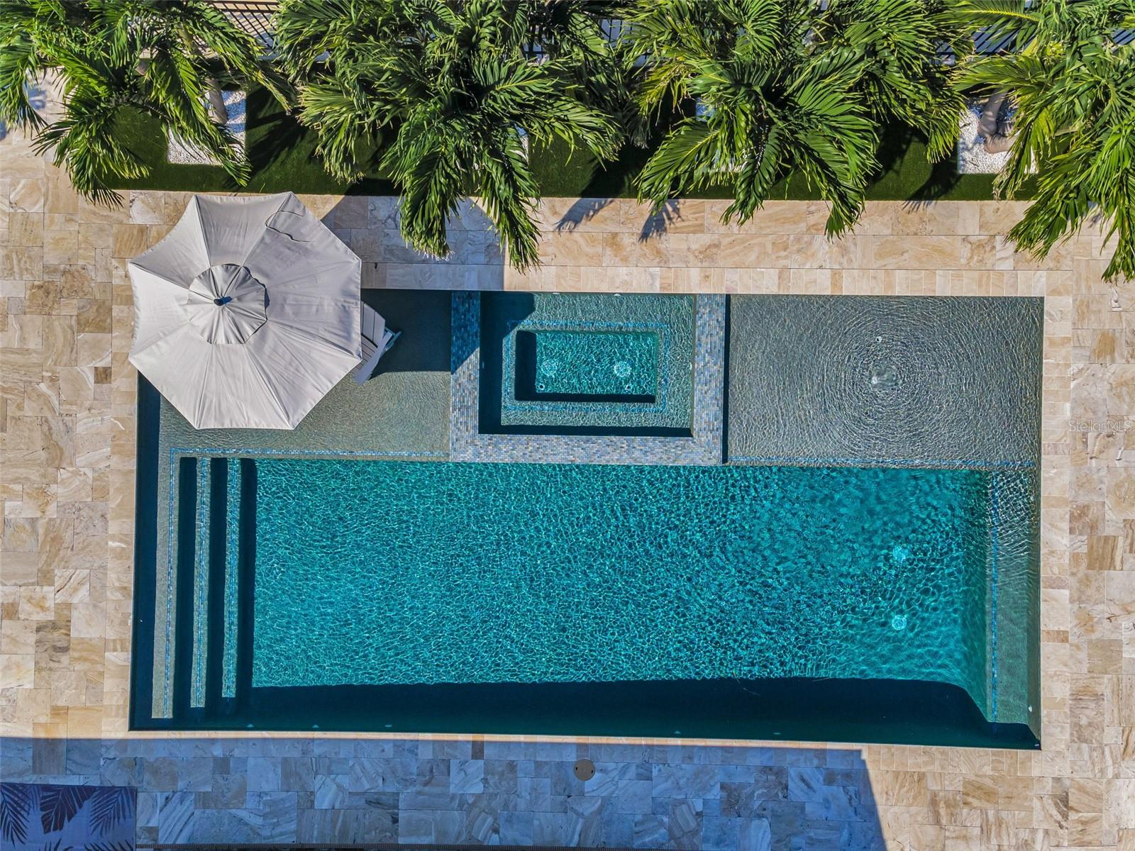This pool is perfect for entertaining with two oversized sun shelves, a spa, and gorgeous travertine decking.