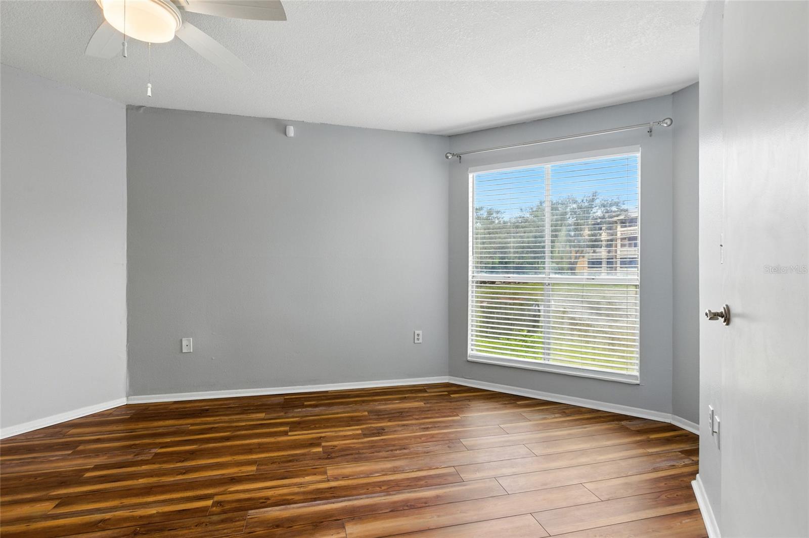 Primary bedroom with LVP flooring, neutral tones, and a large window capturing lake views