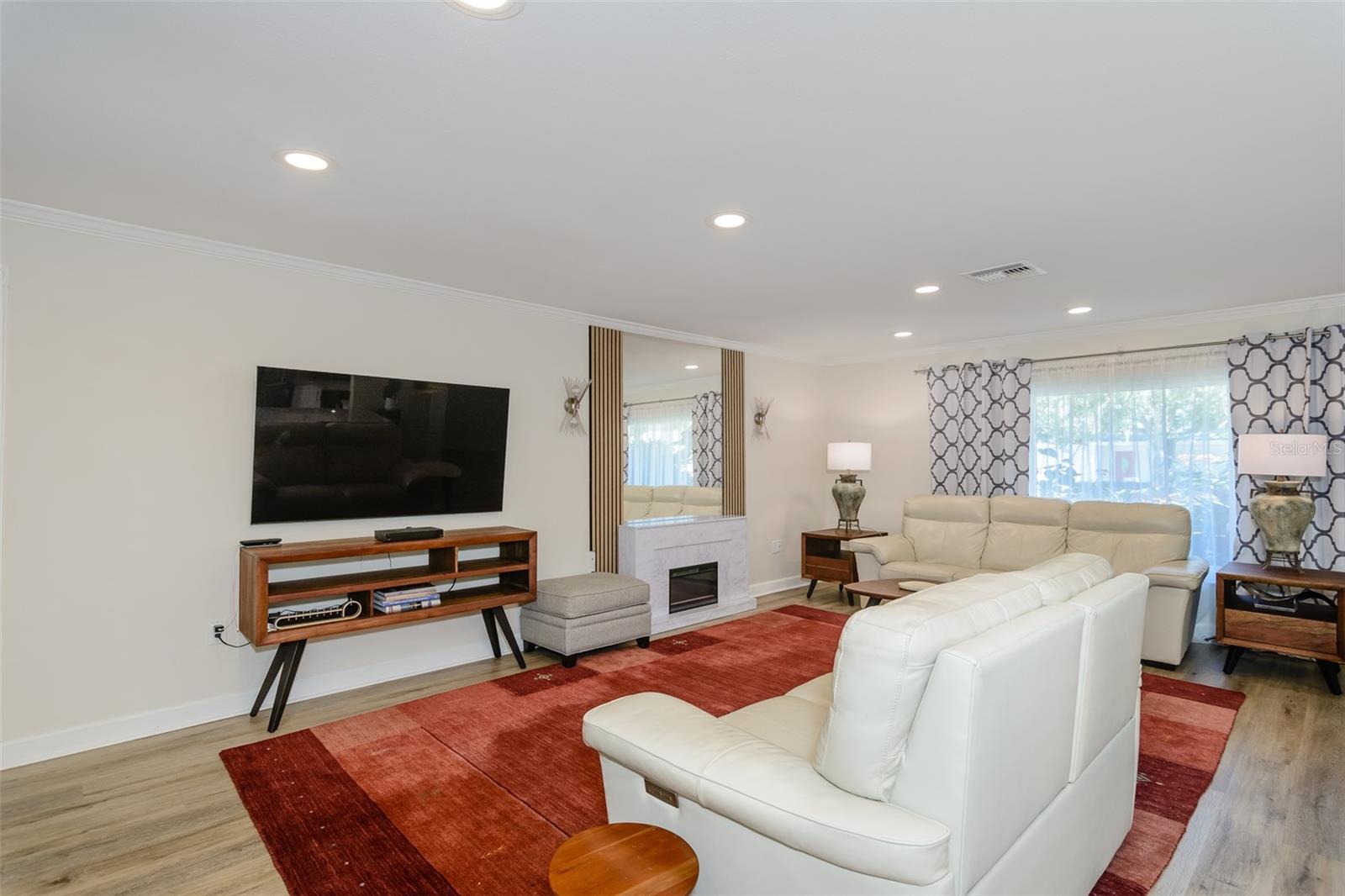 Living room has built-in mirror above the electric fireplace.