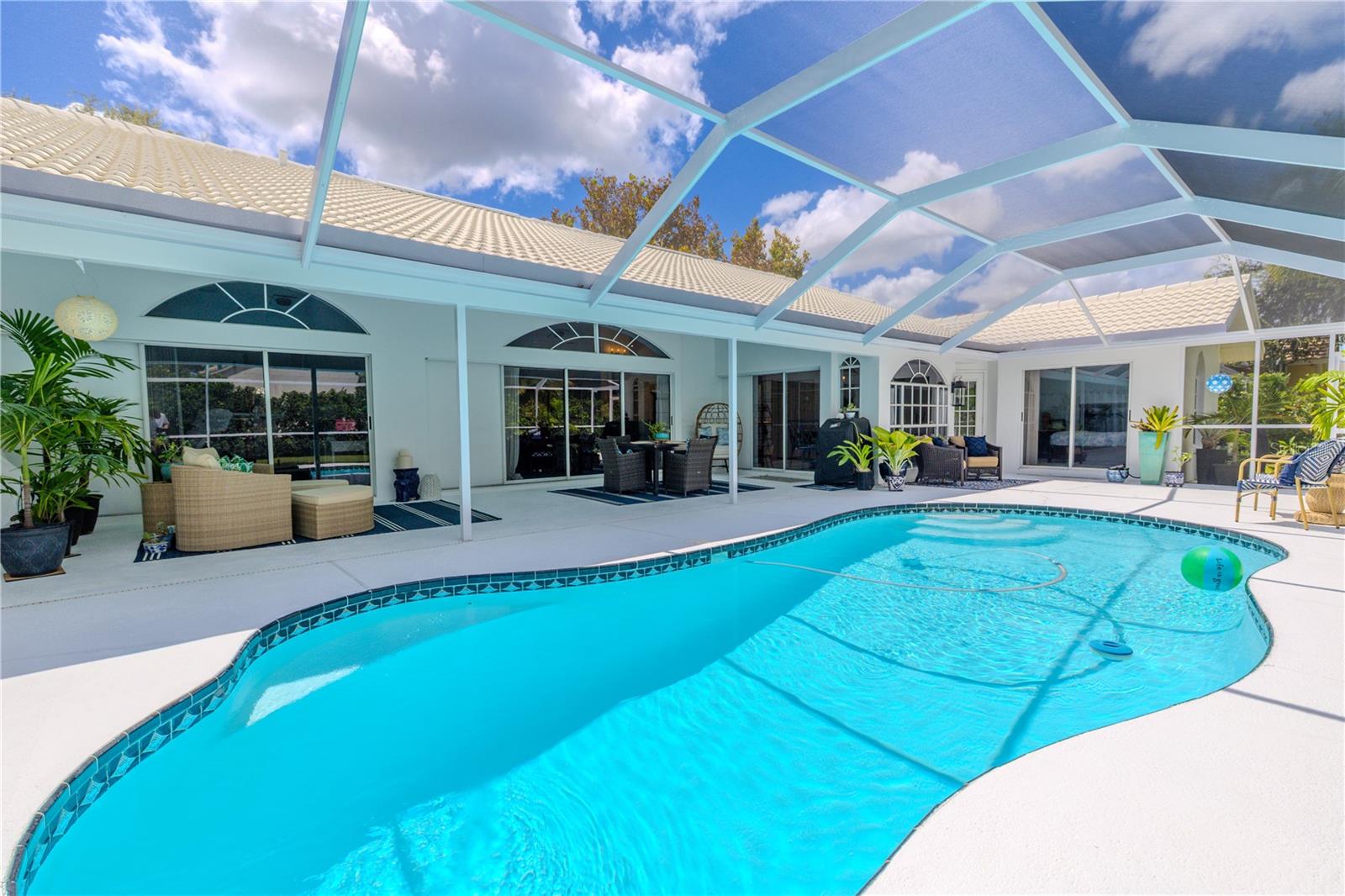 Screen-enclosed pool with spacious lanai, arched windows, and multiple sliding glass doors providing direct access from the interior living areas.