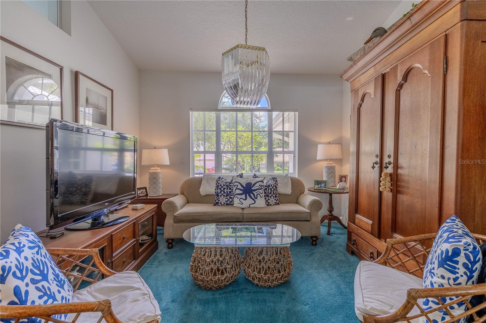 A versatile flex room with large front-facing window and chandelier, ideal for use as a home office, study, or cozy sitting area.