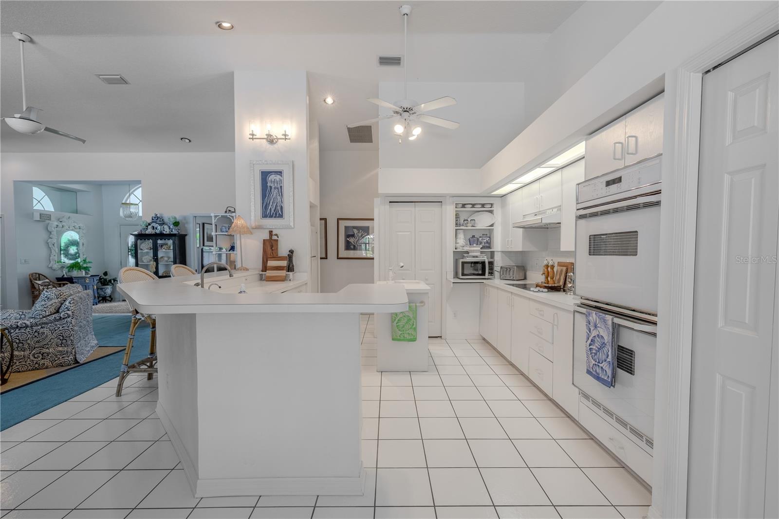 The kitchen is finished with ceramic tile flooring, bright white cabinetry, and ample counter space, all designed for easy upkeep and everyday functionality.