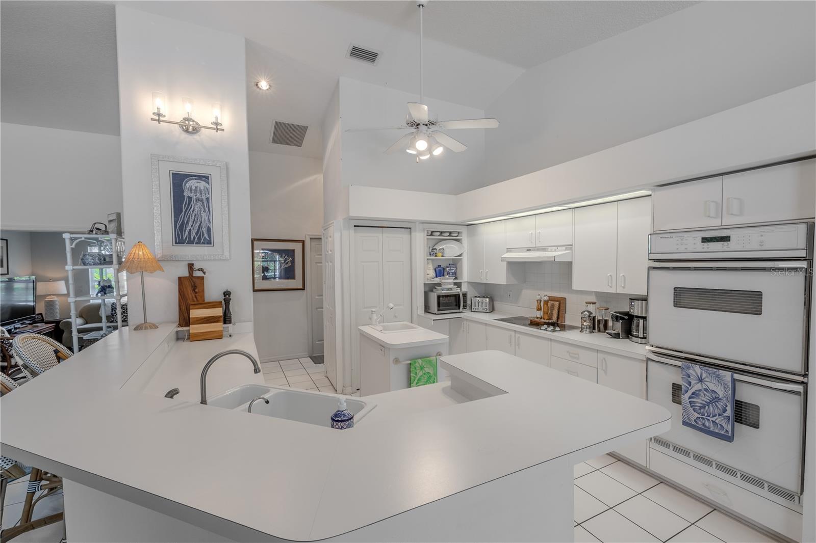 This kitchen is designed for gatherings, with a spacious breakfast bar offering plenty of seating, a center island, and double ovens for easy entertaining.