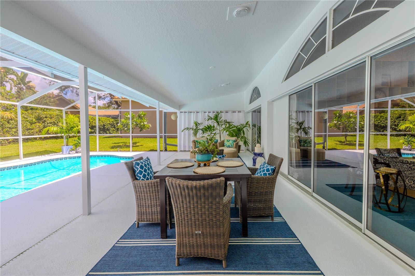 Covered lanai overlooking the screened pool, with plenty of space for outdoor dining and lounging year-round.