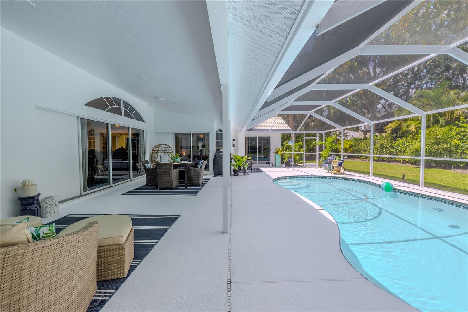 Expansive covered patio runs the length of the pool, offering shaded seating areas and seamless access to the backyard.
