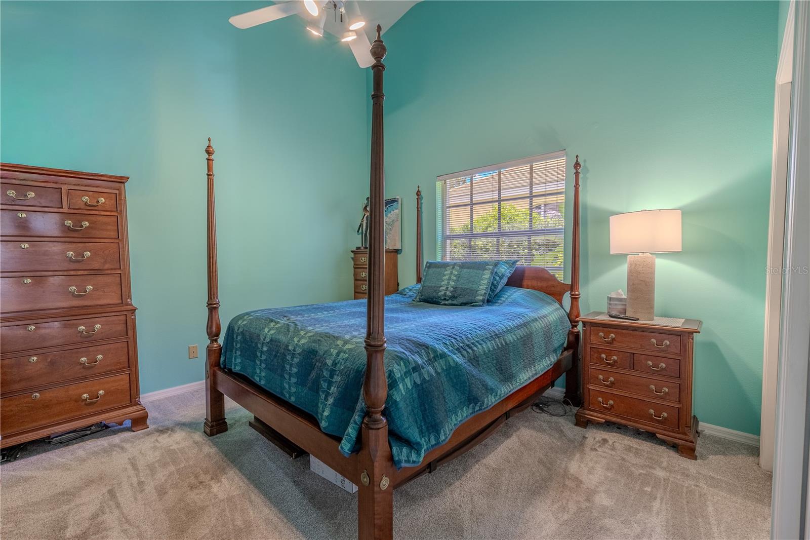 The third bedroom features a vaulted ceiling with a ceiling fan, plush carpet flooring, and a large window that fills the space with natural light.
