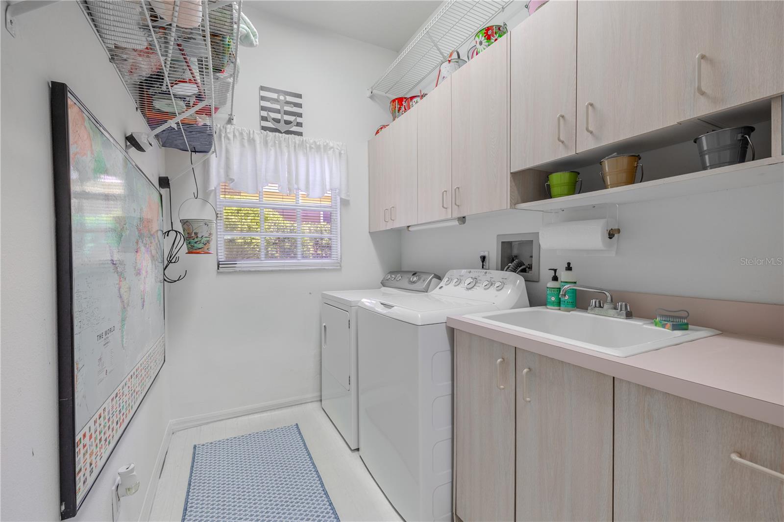 Practical laundry space complete with washer, dryer, deep utility sink, and plenty of built-in storage.