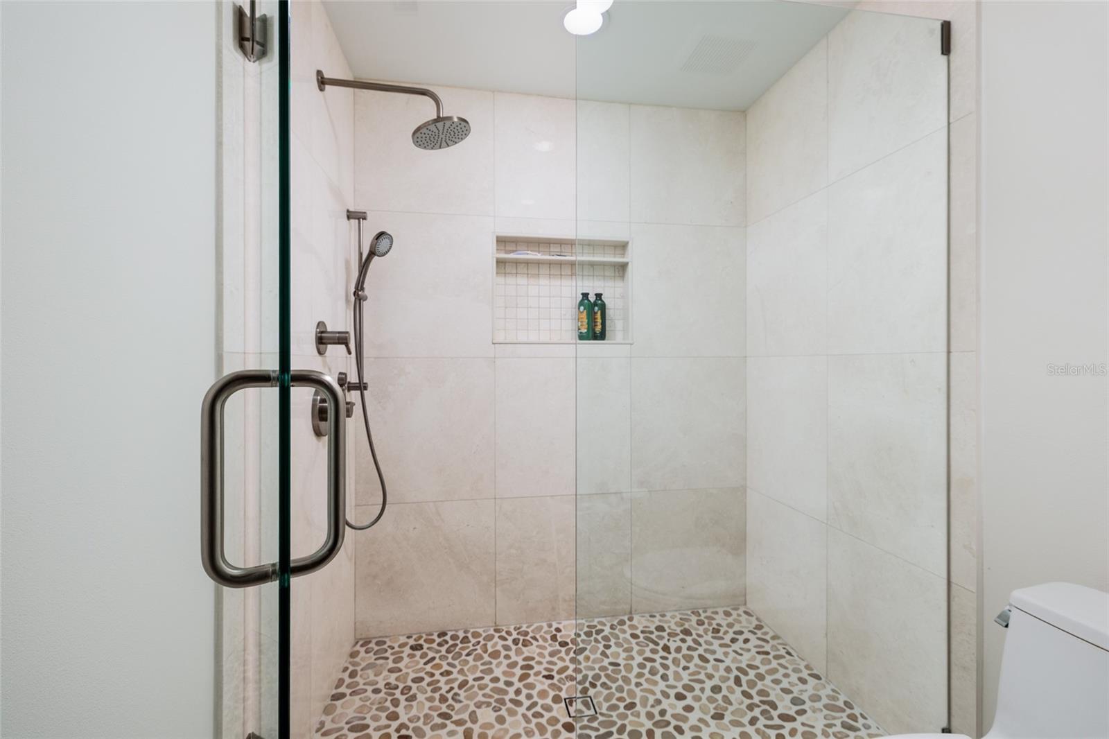 Frameless glass shower with pebble stone flooring