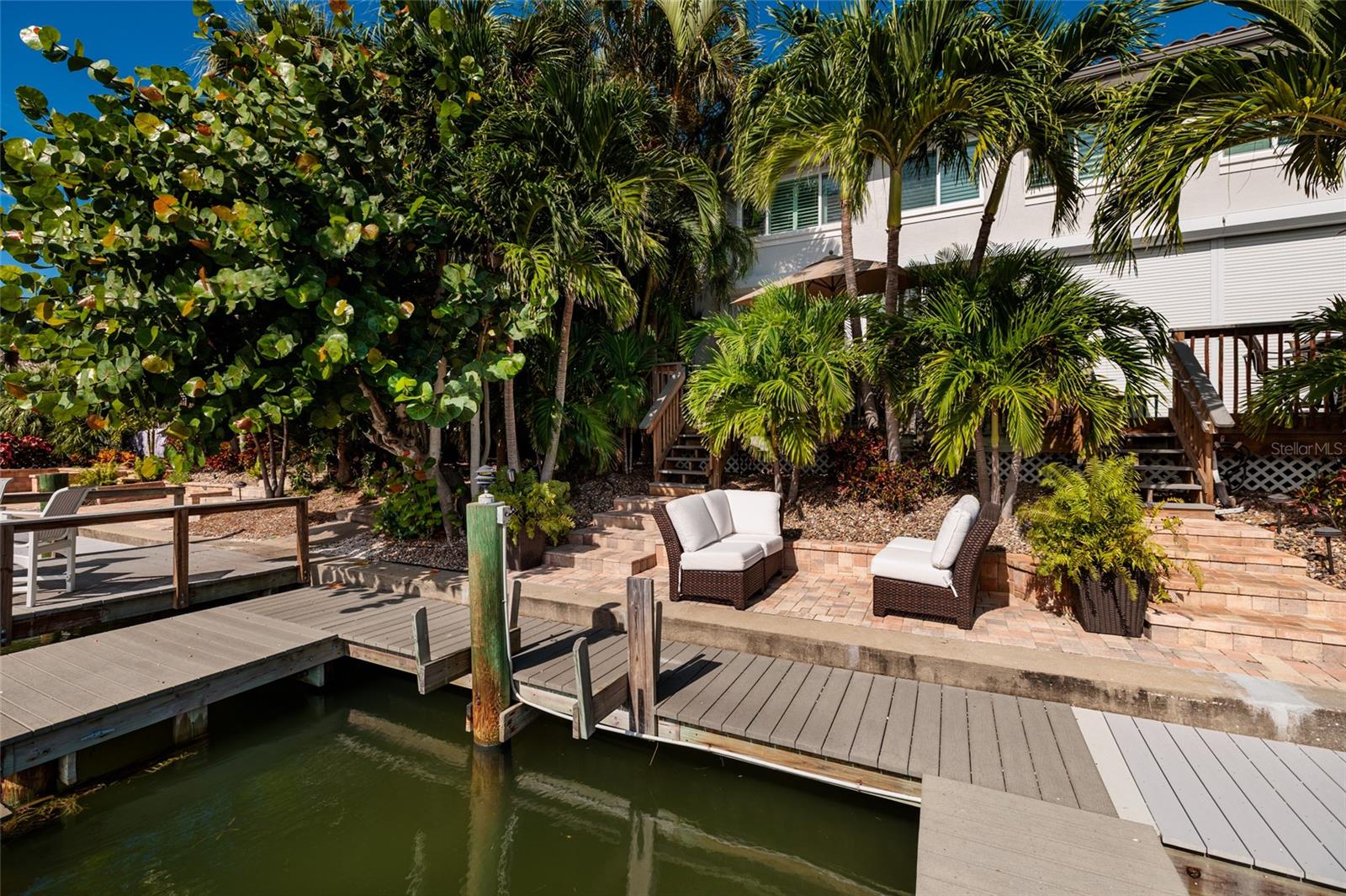 Pavered patio shaded by palms, perfect for relaxing waterside