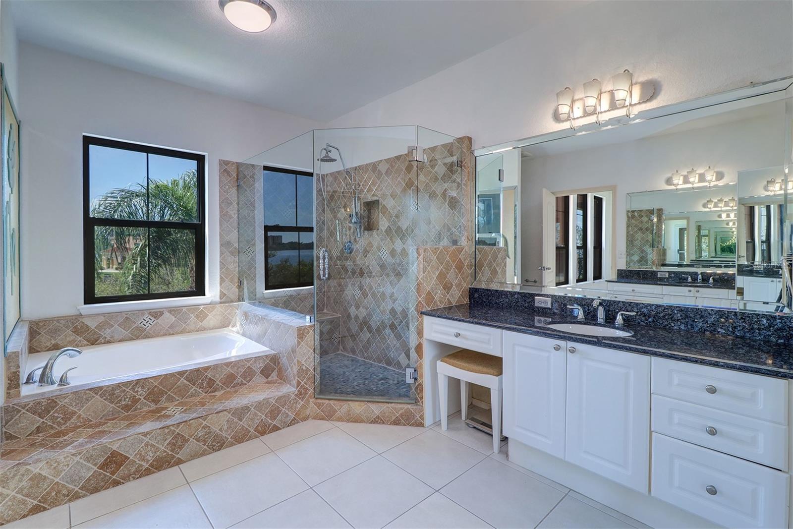 Primary bathroom with updates to garden tub, shower and glass enclosure; separate vanities with granite counter tops and small make up area