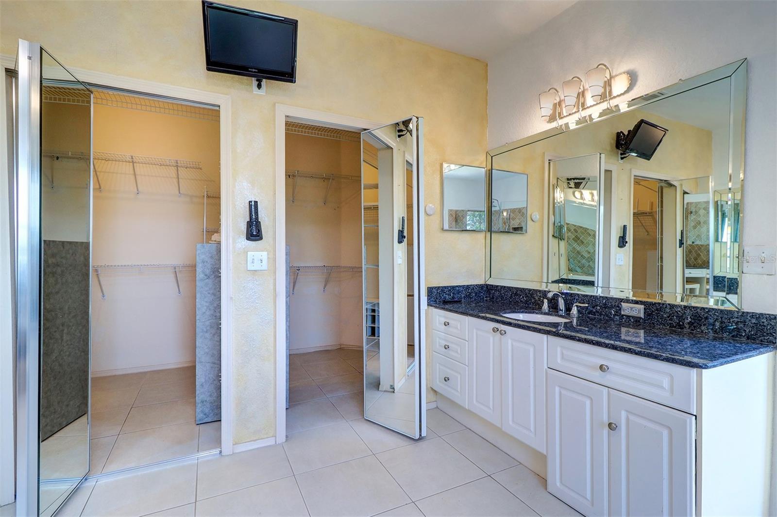 Second vanity and view of walk in closet with mirrored doors