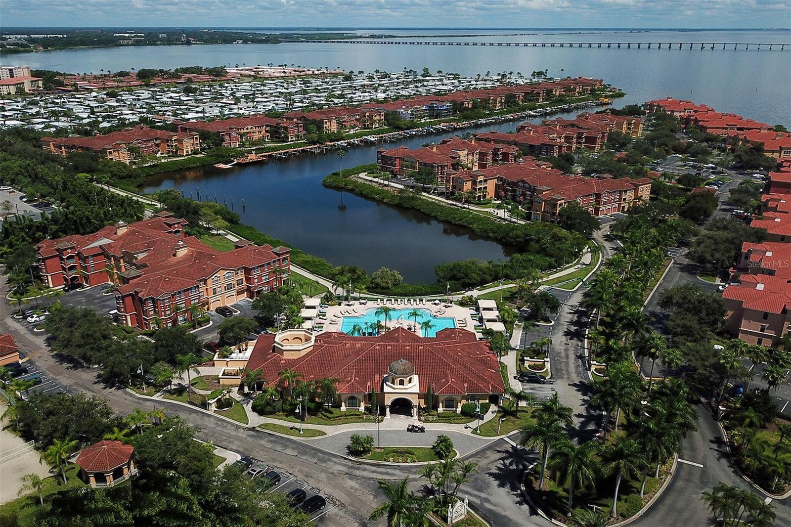 Aerial view of the front of The Grand Bellagio clubhouse, pool and bayou/inlet out into Old Tampa Bay