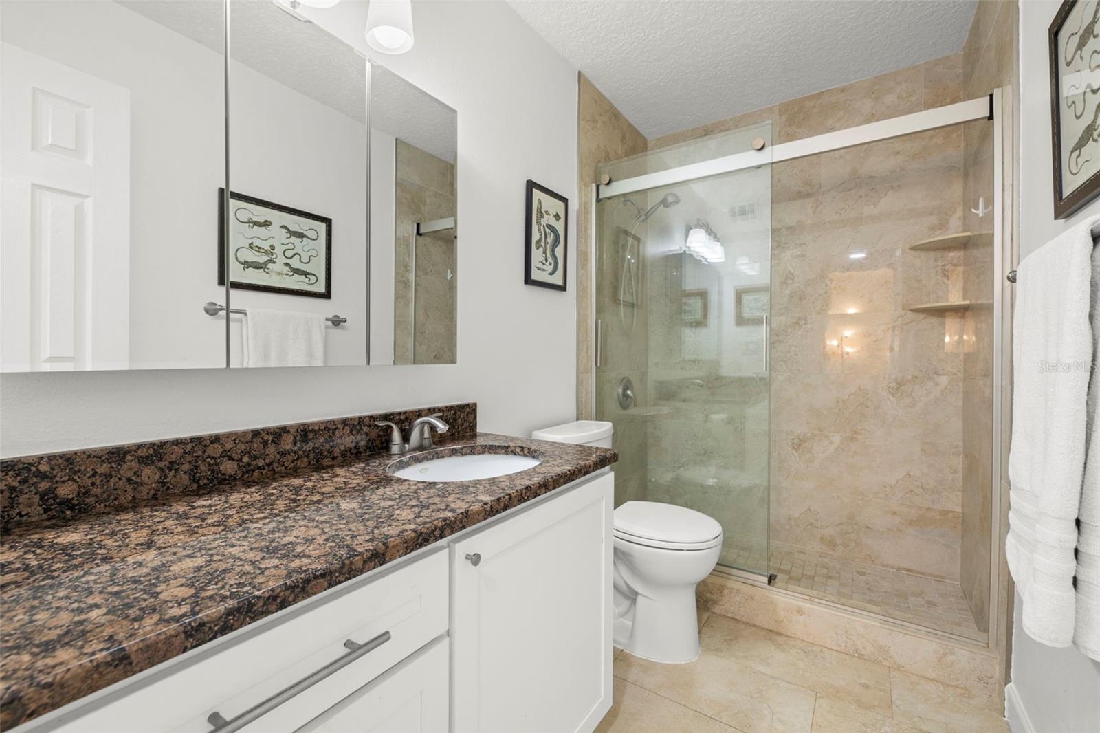 Updated Bathroom with new tile, granite vanity, glass shower door, and modern finishes.