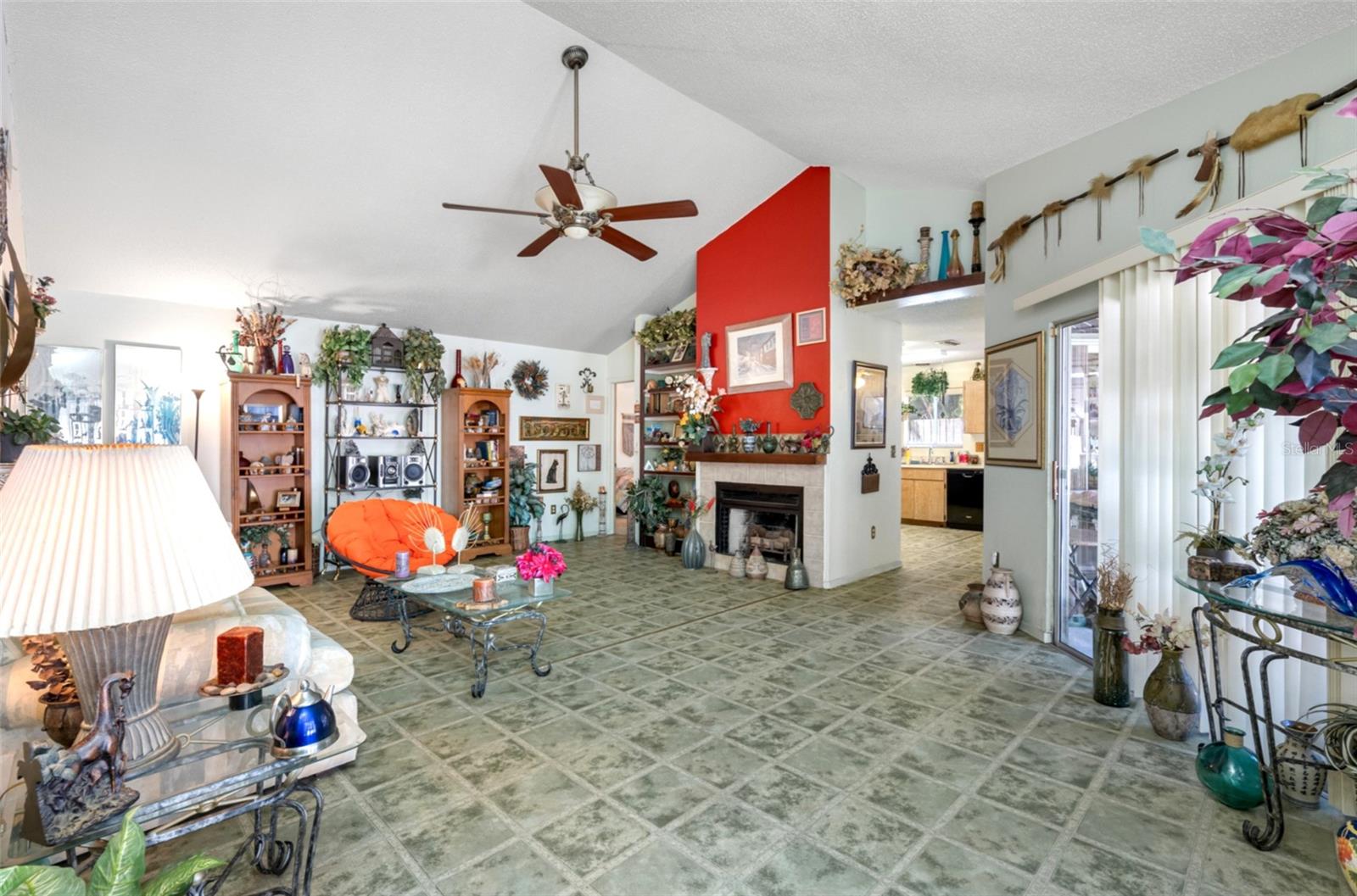 Large living room with wood-burning fireplace looking into the kitchen
