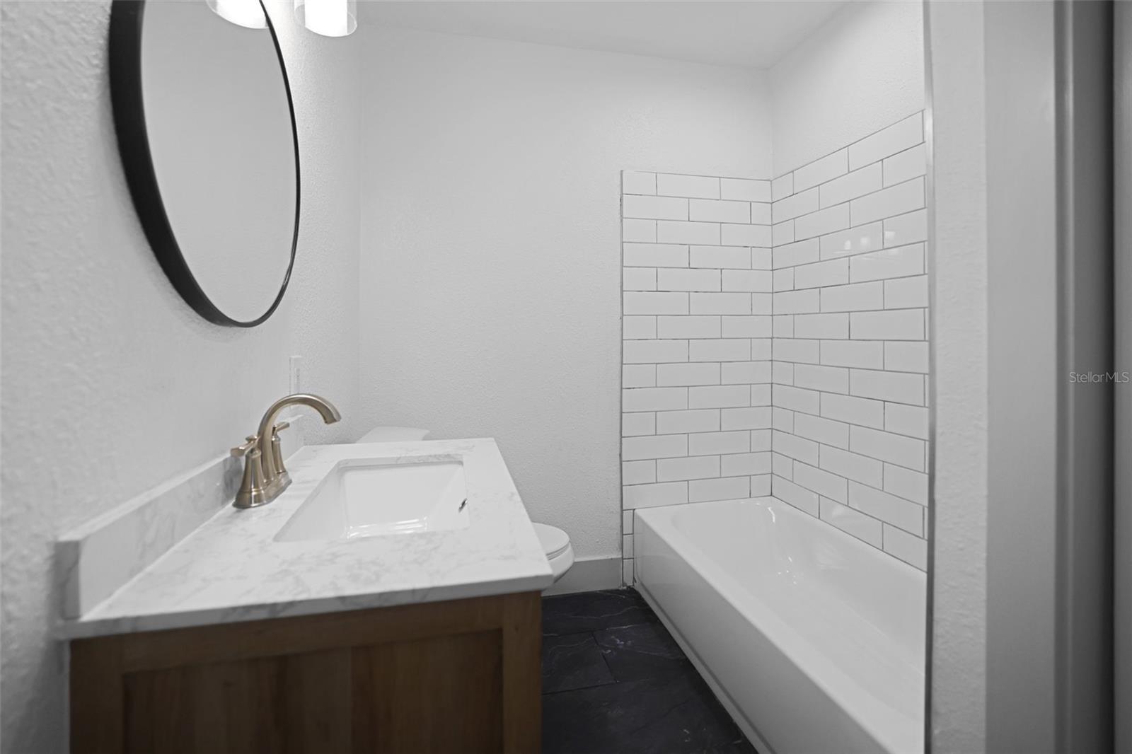 Bathroom 1 - new tile flooring - new bathroom vanity- new faucets - new mirror - new light fixture-new tub- new tile around tube - freshly painted