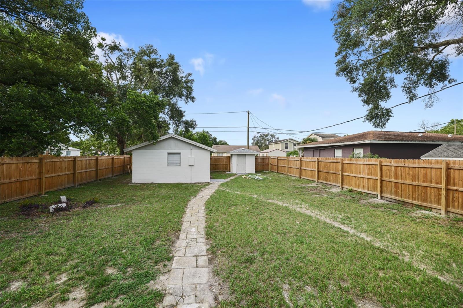 Large back yard with view of the back of the garage and separate storage shed- fully fenced