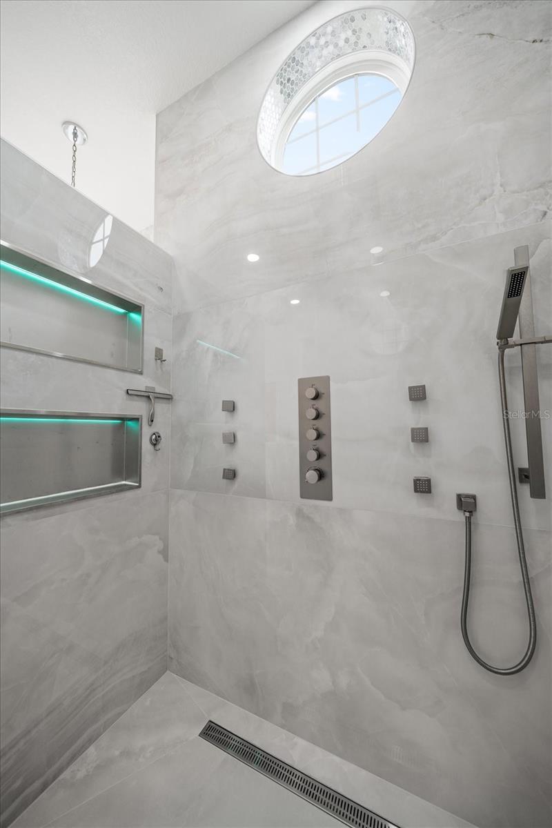 Walk-in shower in the primary bathroom, featuring multiple shower head features.