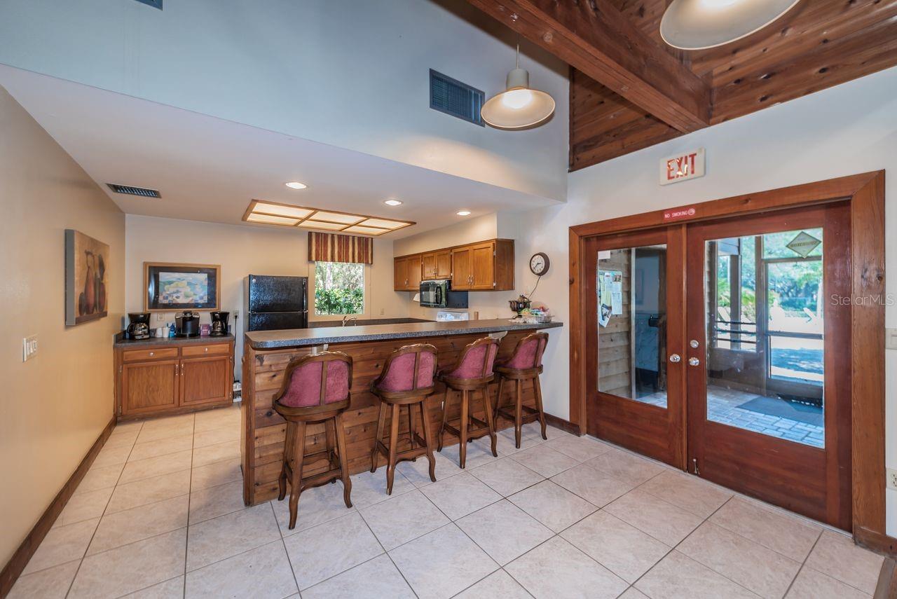 Clubhouse offers a fully equipped kitchen. French doors open to screened porch and then the pool area.