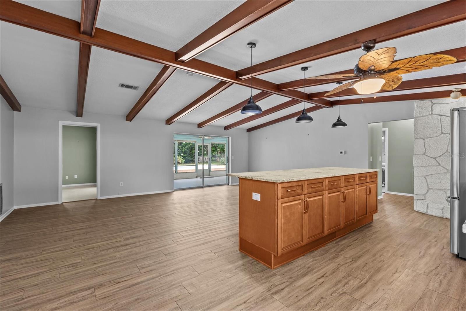 Open concept great room with luxury vinyl plank floors, vaulted ceilings and exposed wood beams.