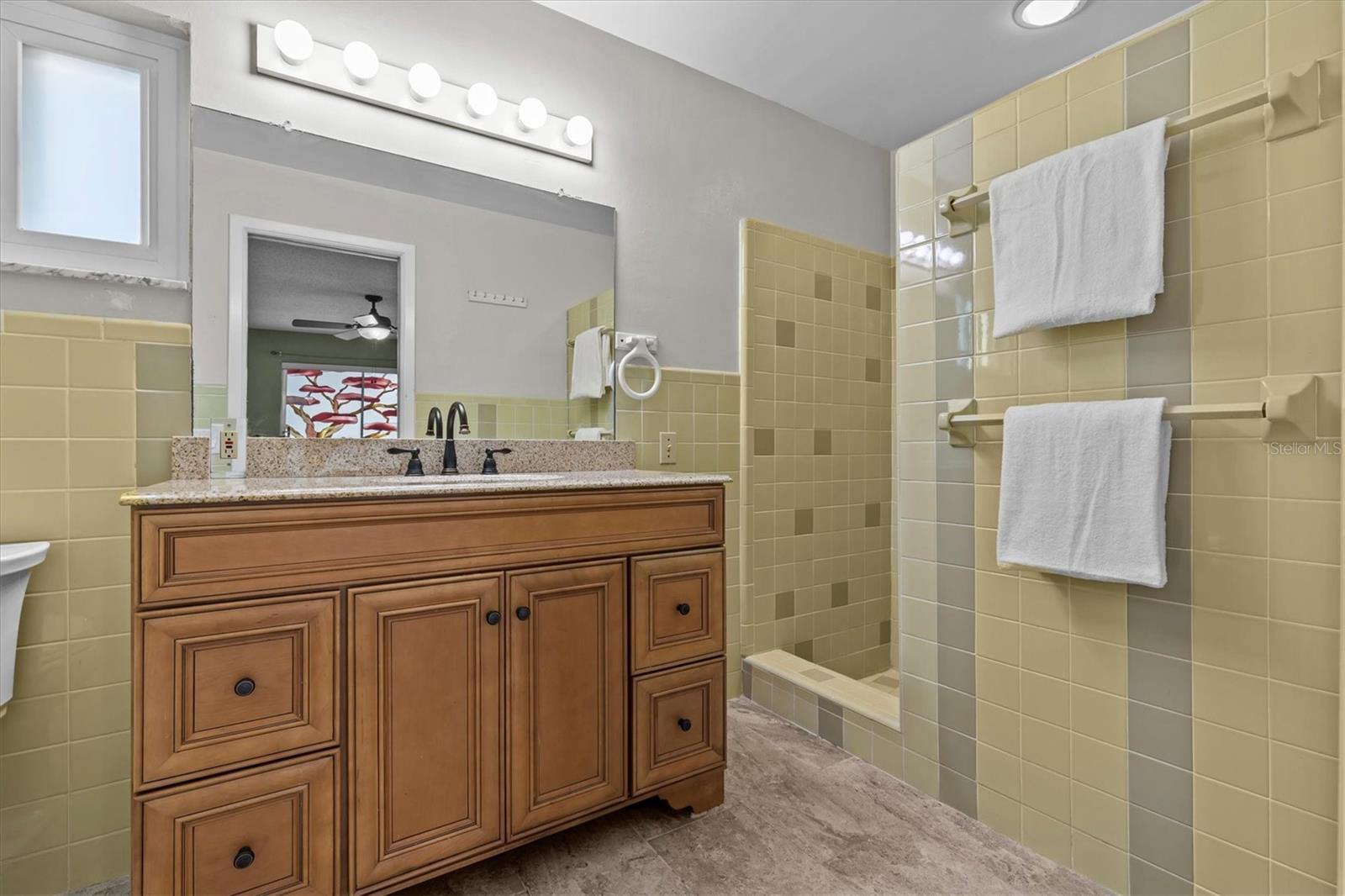 Tile primary bath with European cabinetry and sunken tub/shower.