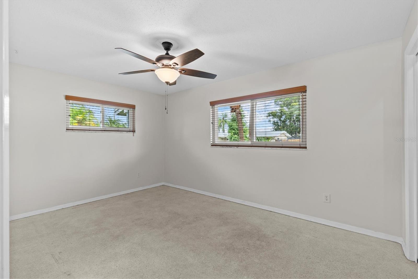 Bedroom 2 with original terrazzo floors and custom wood blinds.