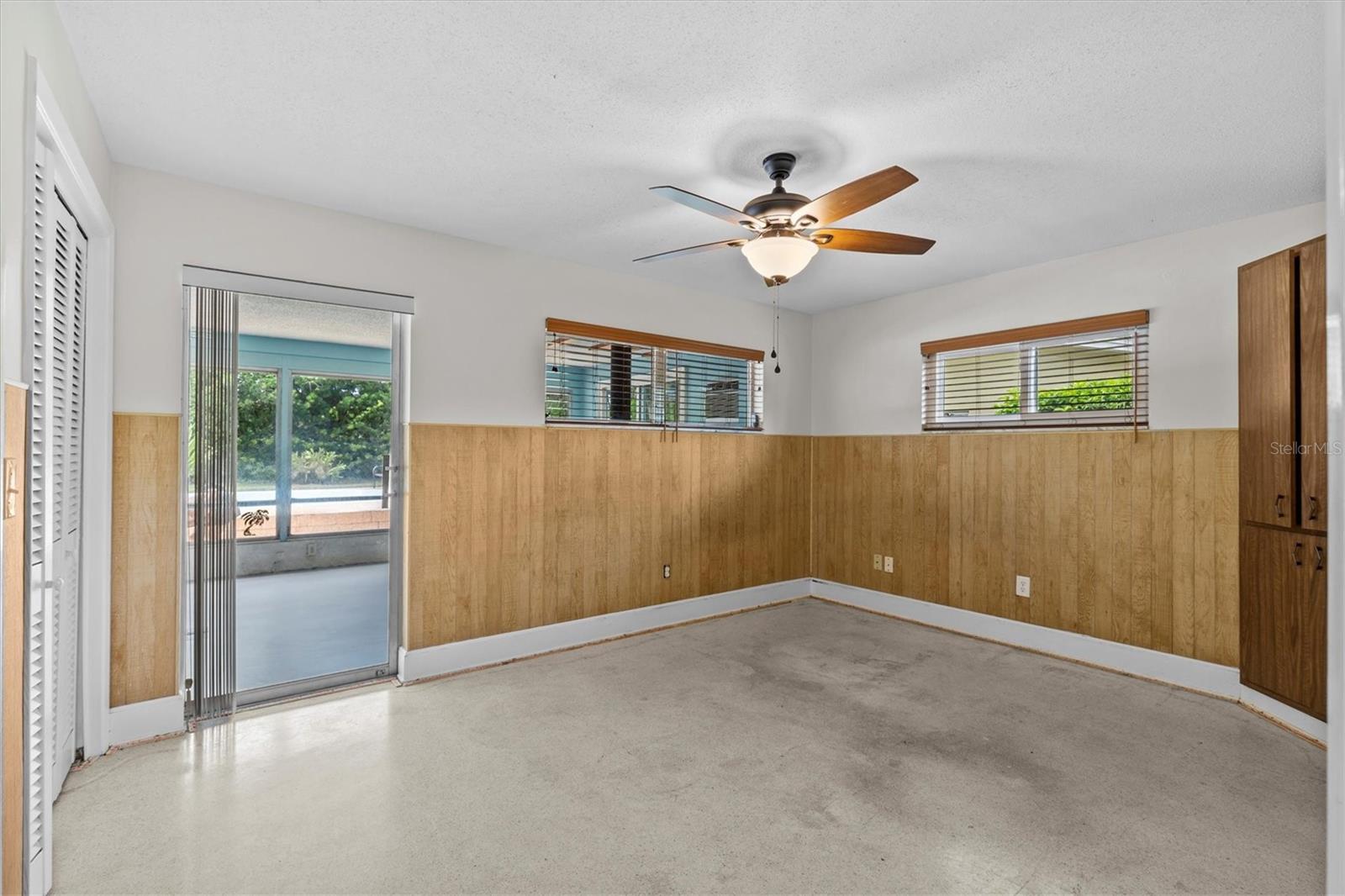Bedroom 3 with terrazzo floors, slider to lanai and custom wood blinds.