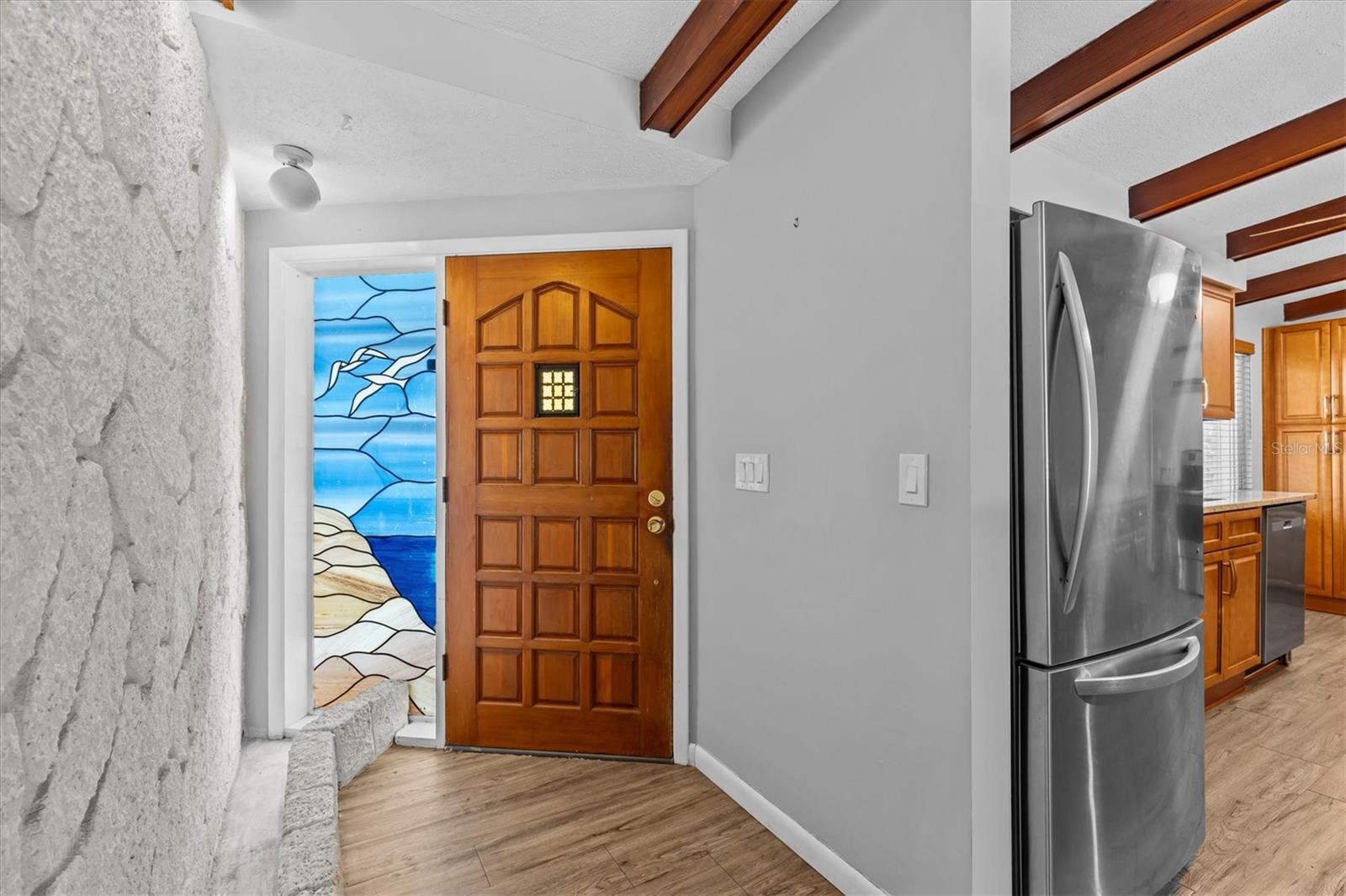 Foyer with custom stained glass window and hurricane shutter.