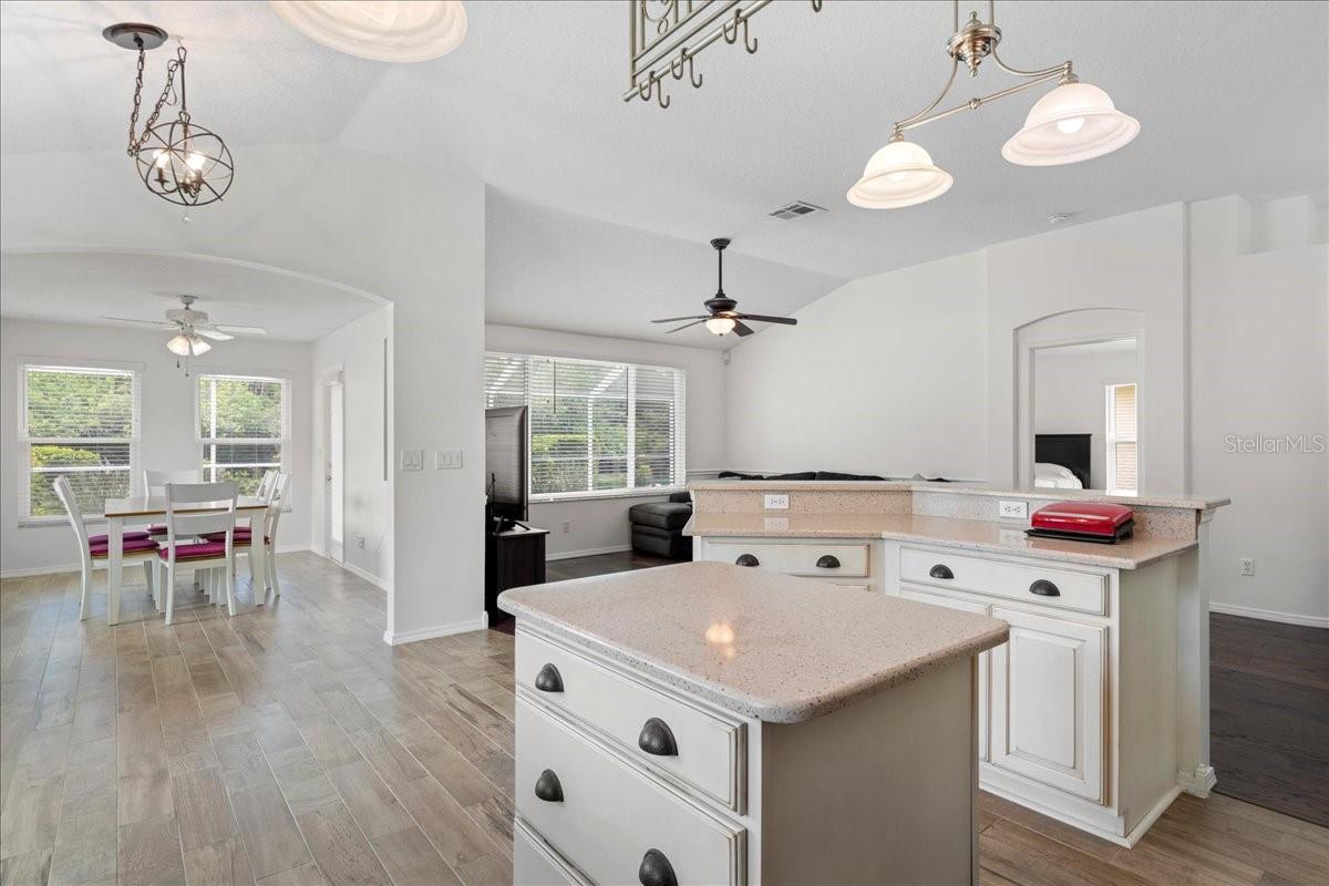 At the center of the home, the light and bright open concept kitchen boasts all wood custom cabinets with pull out drawers, garnet countertops, a breakfast nook in a bay window, nice-sized pantry, center island offering additional prep and storage space, stainless-steel appliances, and a raised breakfast bar countertop overlooking the living room and dining room.