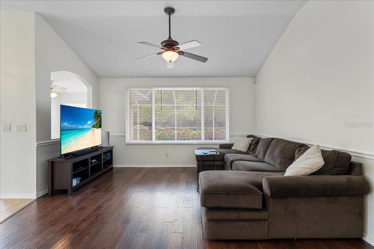 Living room with vaulted ceilings and large windows with views of pool and pond just beyond.