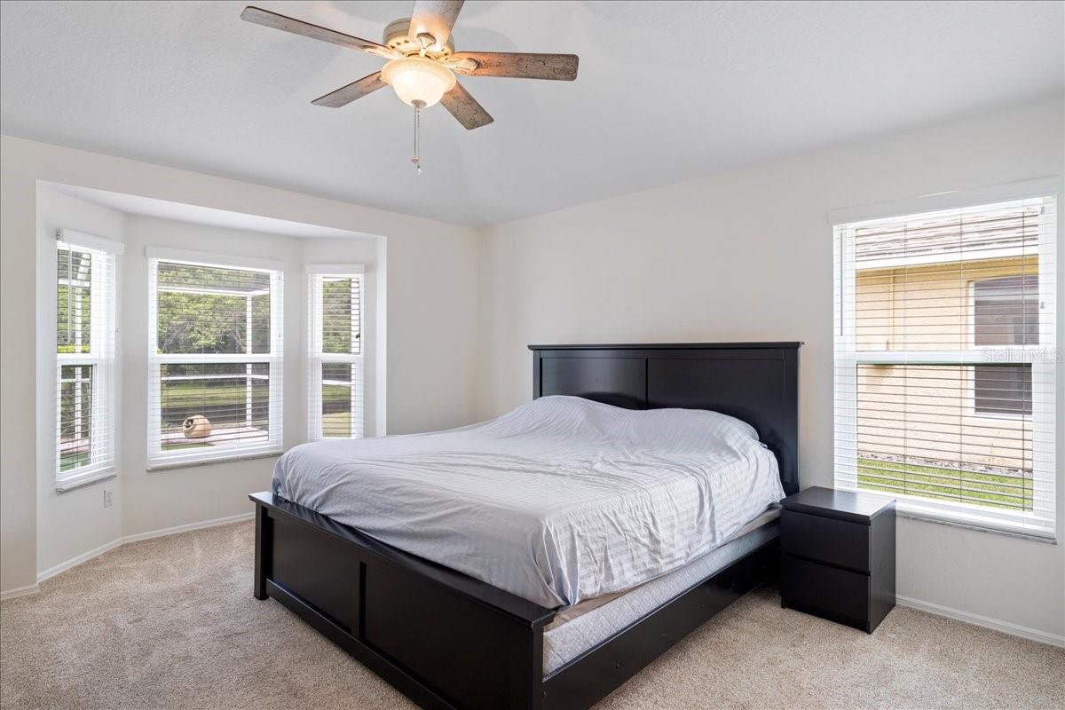 Primary bedroom with bay window views out to pool and pond, two walk-in closets, vaulted ceilings and an ensuite bathroom.