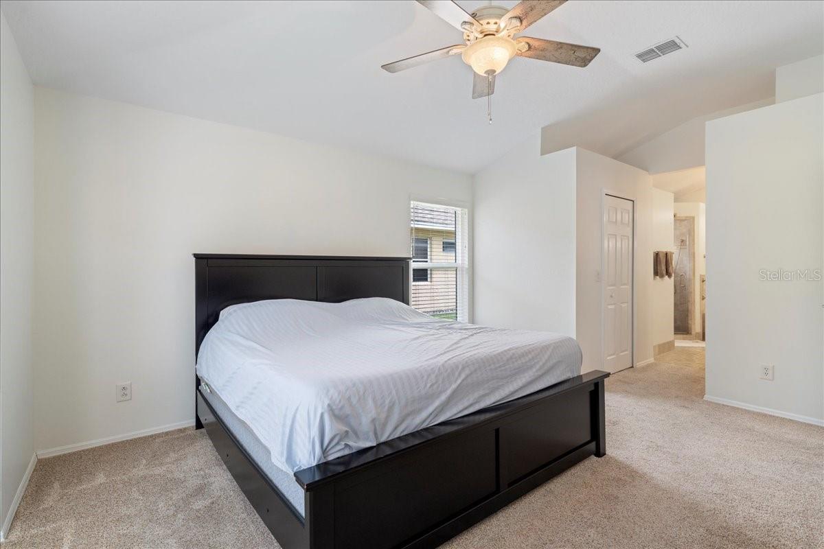 Primary bedroom with bay window views out to pool and pond, two walk-in closets, vaulted ceilings and an ensuite bathroom.