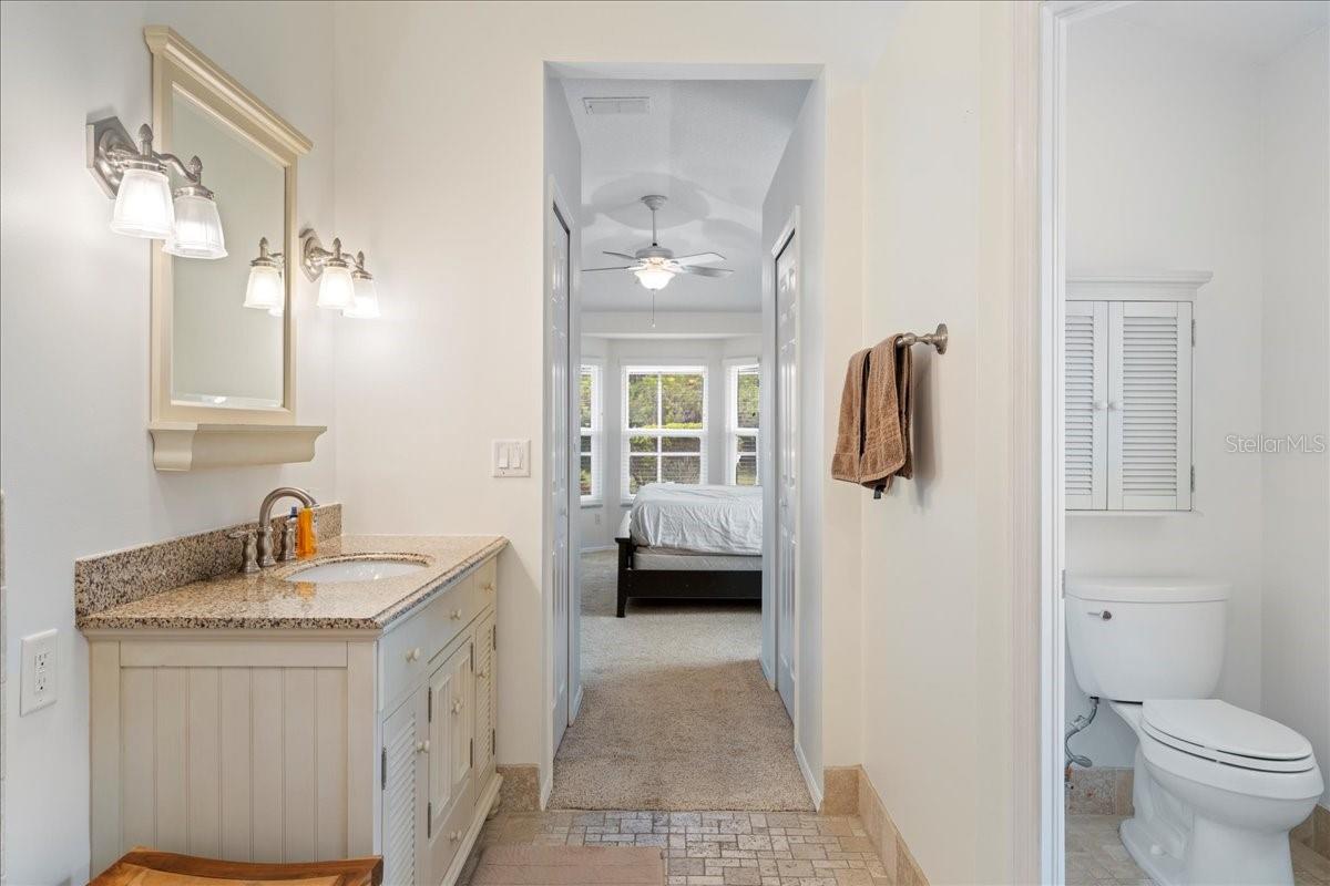 Primary ensuite bathroom featuring a jetted tub, separate Toilet closet, and walk-in shower and spa-like travertine tile accents.