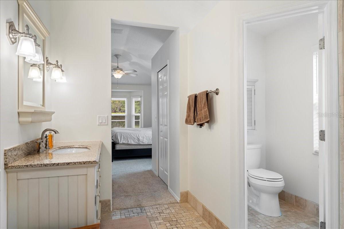 Primary ensuite bathroom featuring a jetted tub, separate Toilet closet, and walk-in shower and spa-like travertine tile accents.