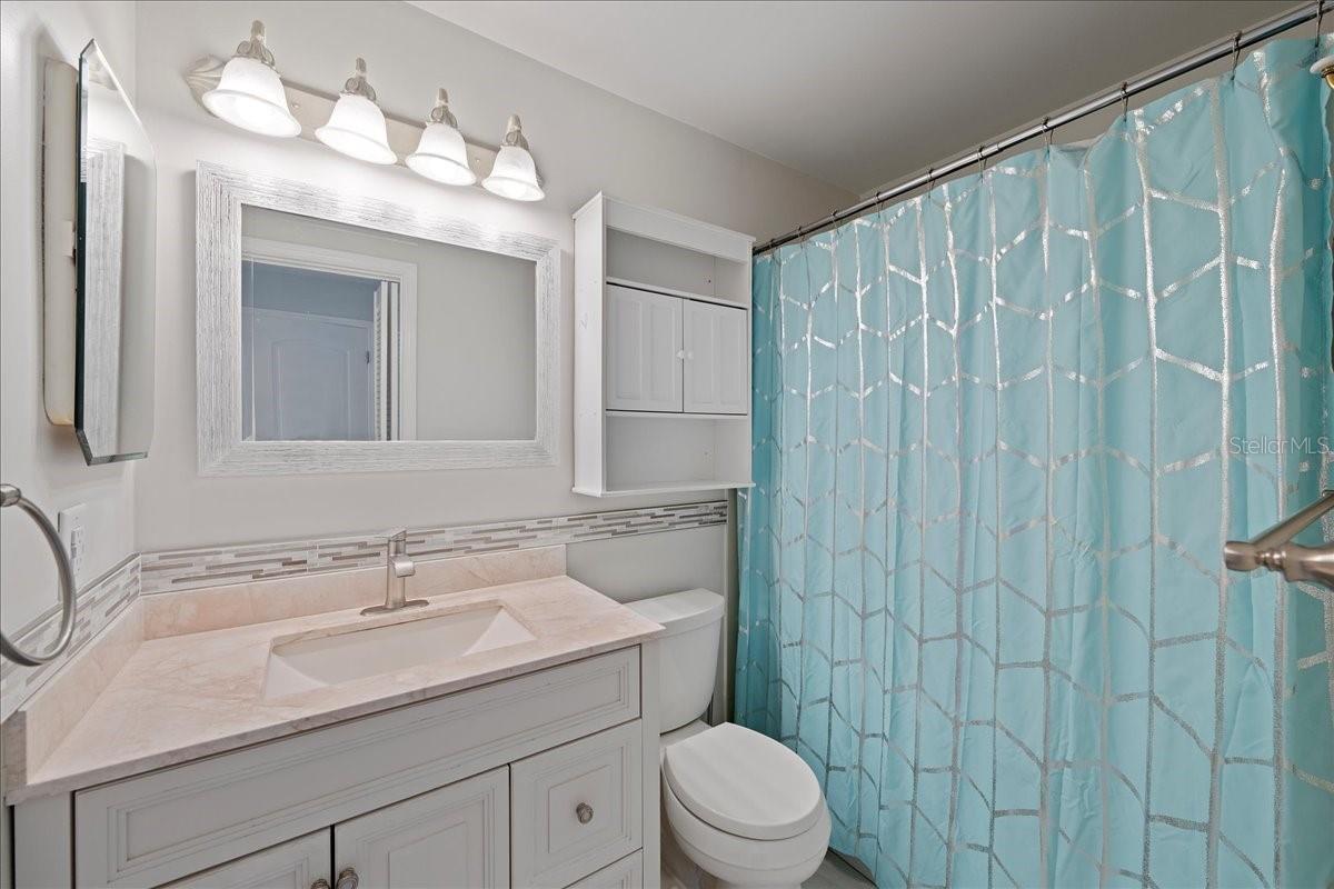 Primary bathroom is light and bright and updated with stylish vanity and shower/tub combo