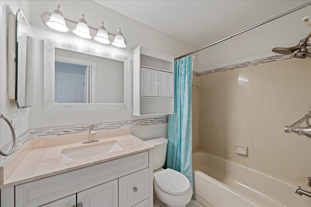 Primary bathroom is light and bright and updated with stylish vanity and shower/tub combo