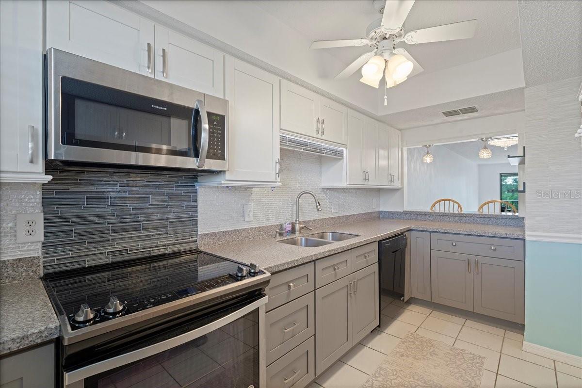 Updated kitchen with neutral colors, Corian countertops, stainless-steel appliances, a stylish backsplash, nice-sized pantry, and a passthrough breakfast bar to the dining room.
