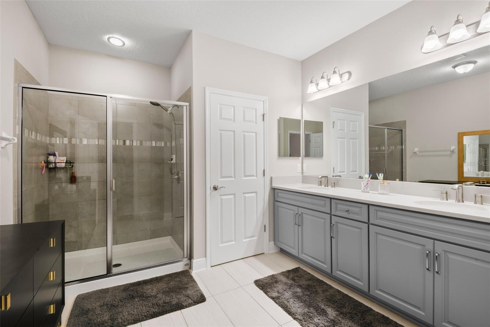 Primary en suite with water closet, step-in shower, dual sink vanity and linen closet