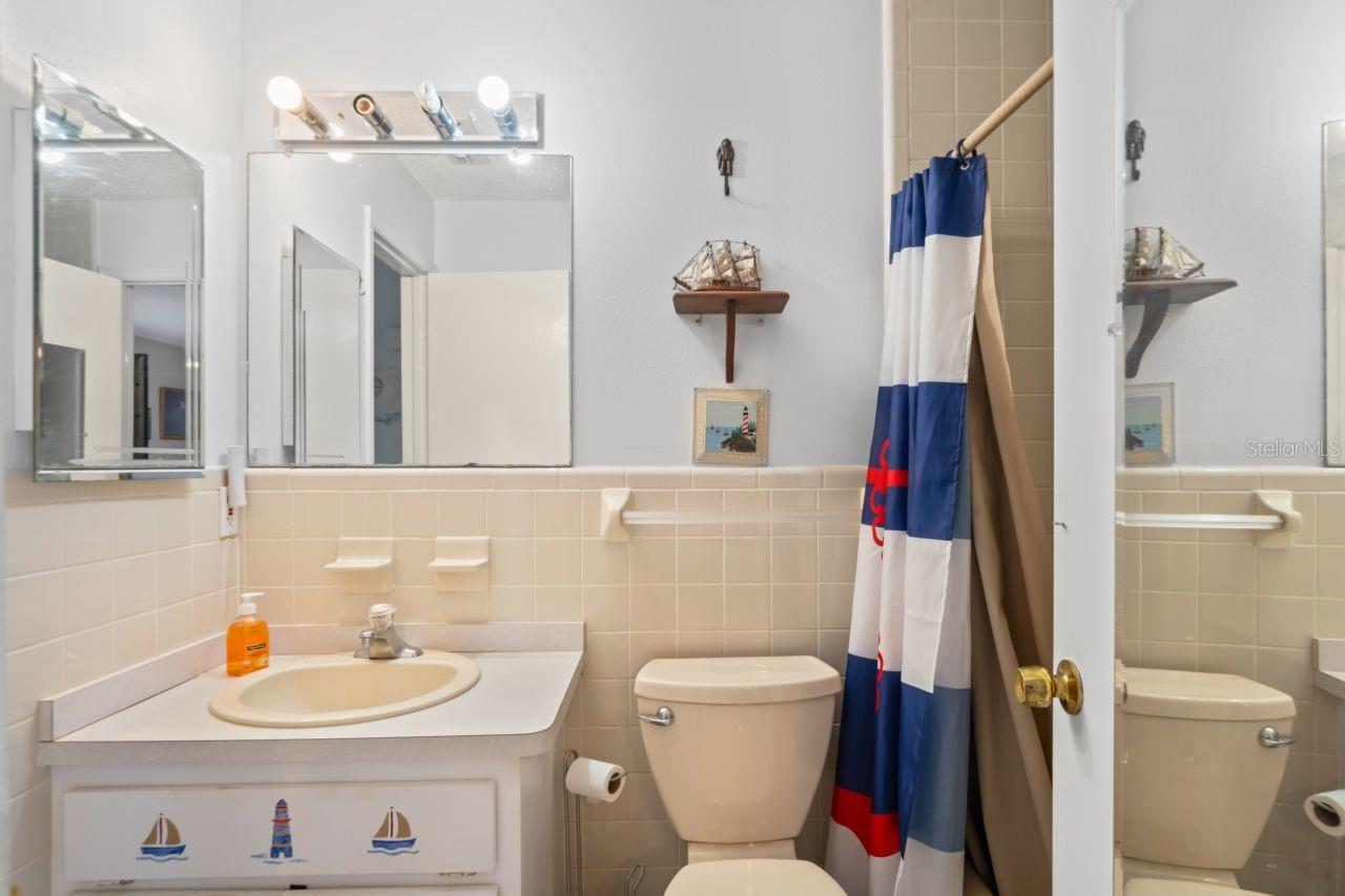 Bathroom offers single vanity, mirrored cabinet, bathtub with shower.